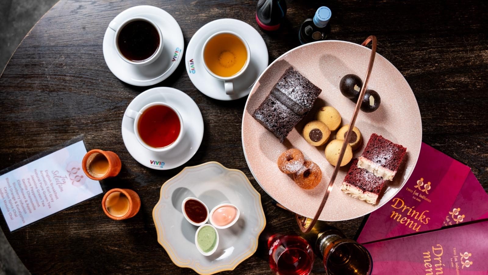 Coffees, teas and desserts laid out on dark timber