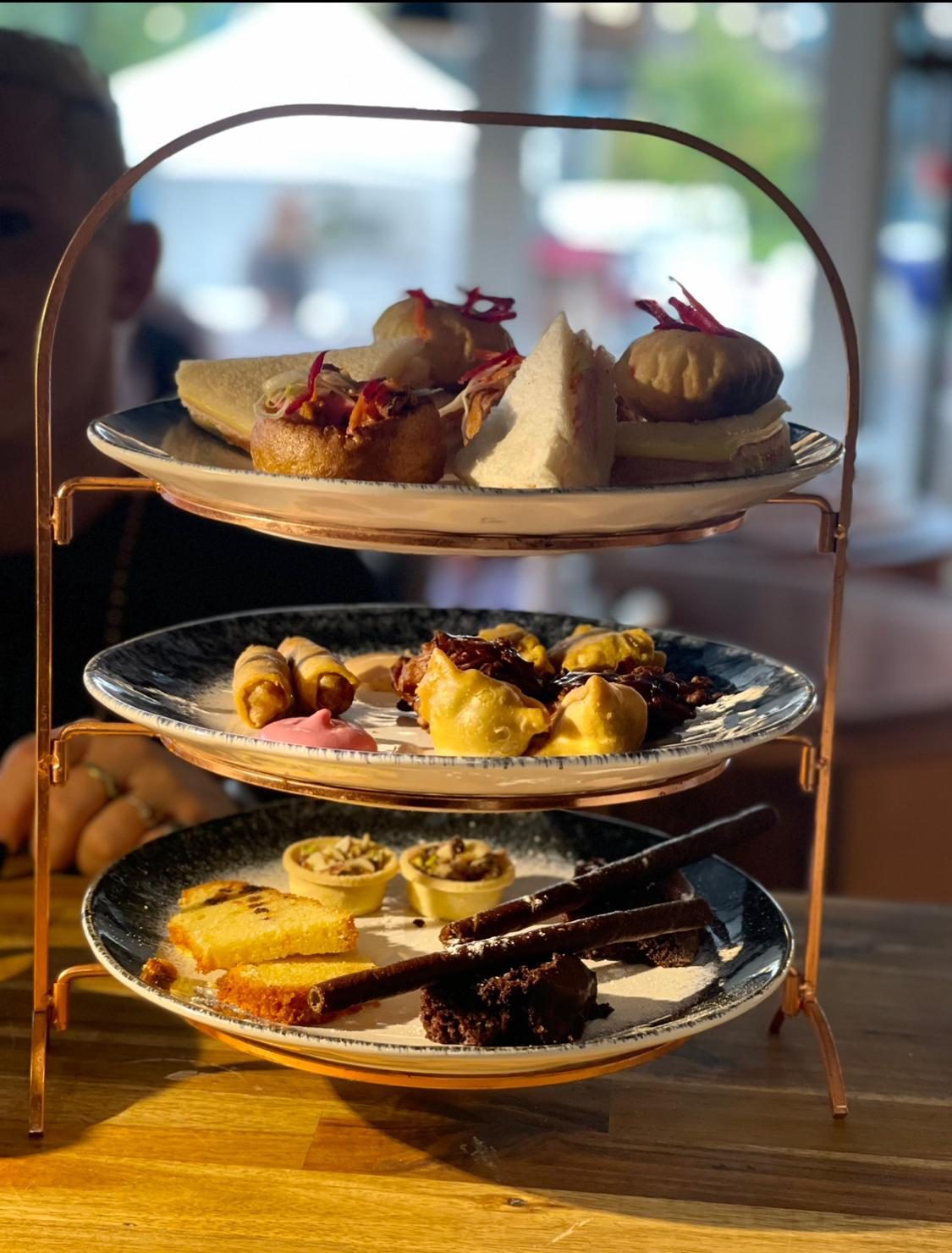 Three-tier high tea stand by a sunlit window